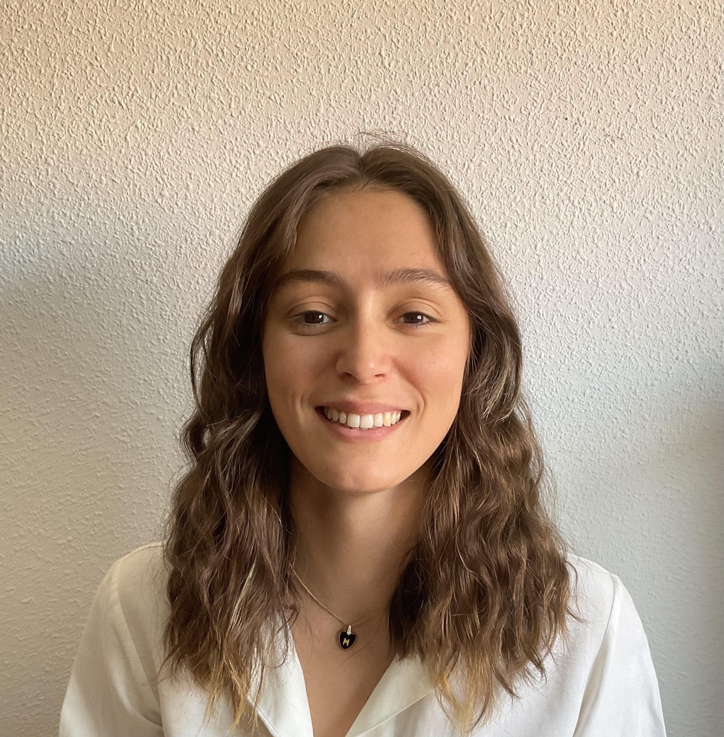 ss Retrato de una psicóloga y profesora de yoga sonriendo, con camisa blanca, transmitiendo cercanía y confianza.