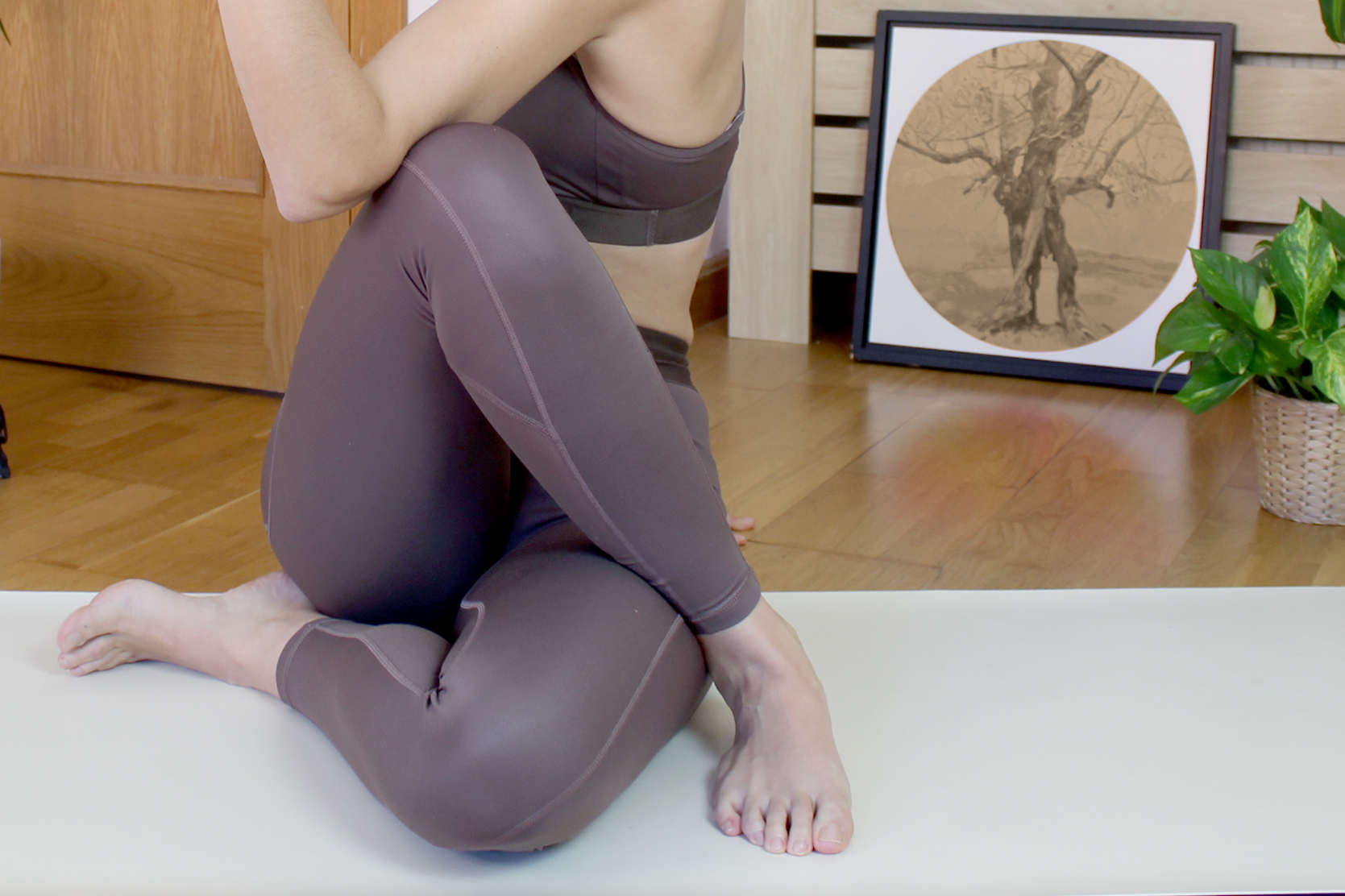Mujer sentada sobre una esterilla realizando una postura de yoga y estiramiento en el estudio de psicoloRia.